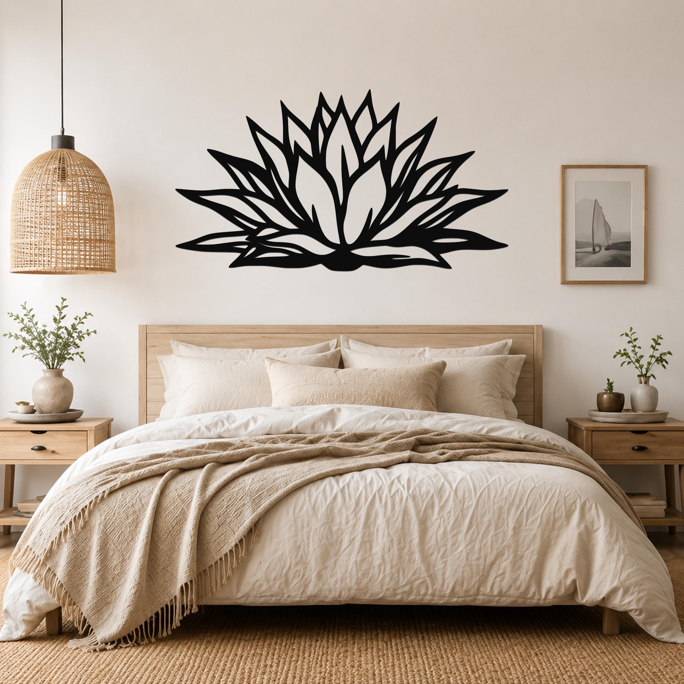 Black metal agave wall art with bold geometric cutouts, mounted above a bed in a neutral bedroom.
