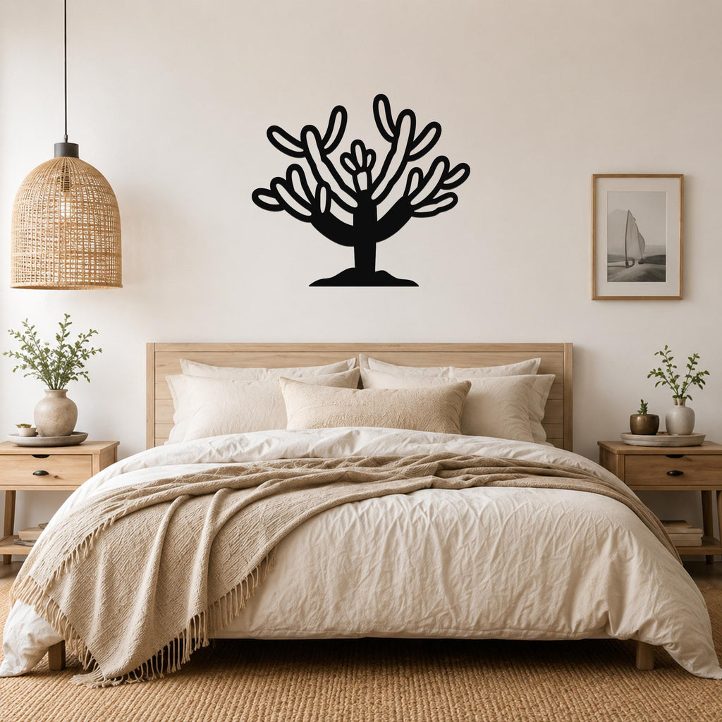 Black metal Cholla cactus wall art with branching cutouts, mounted above a bed in a neutral bedroom.