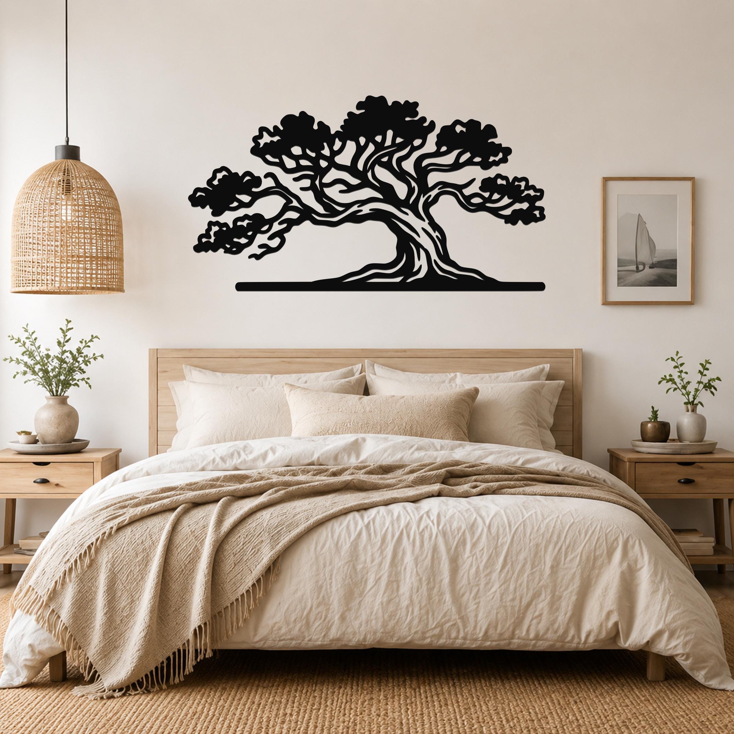 Black metal juniper tree wall art with detailed branch cutouts, mounted above a bed in a neutral bedroom.