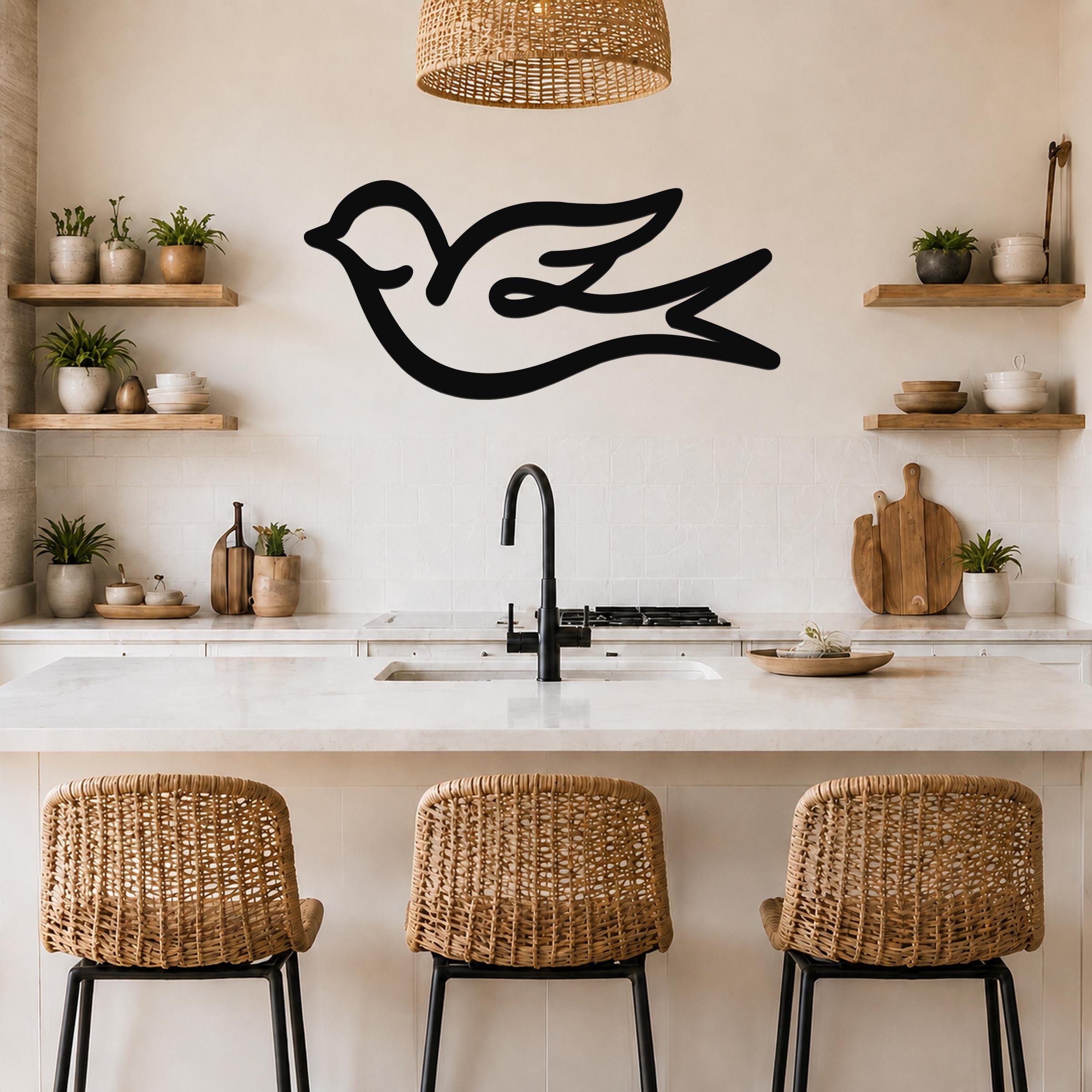 Black metal swallow bird wall art with flowing silhouette lines, mounted above a kitchen counter in a bright, modern kitchen.