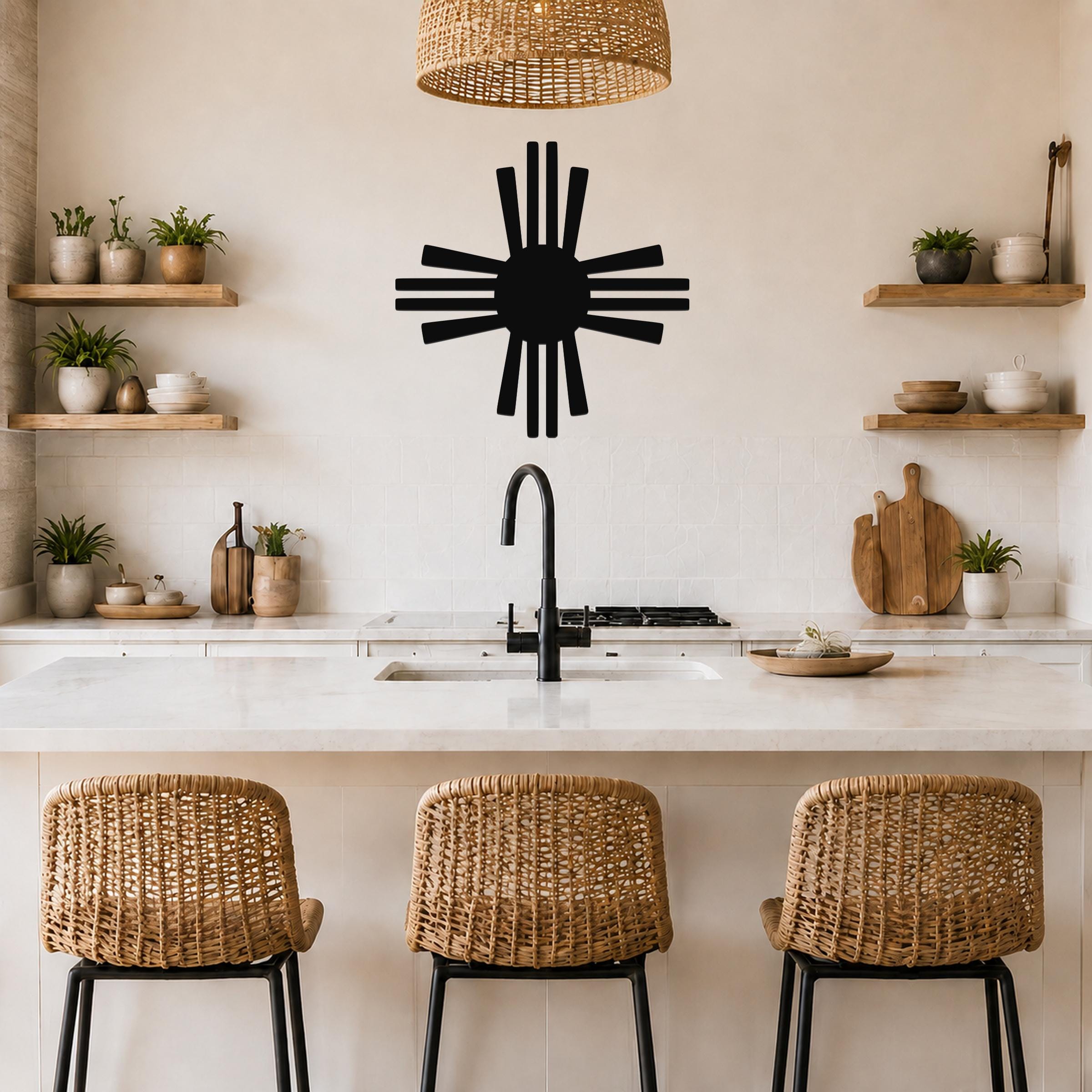 Black metal Zia Sun symbol wall art with radiating rays, mounted on a kitchen wall above a counter with wicker bar stools.