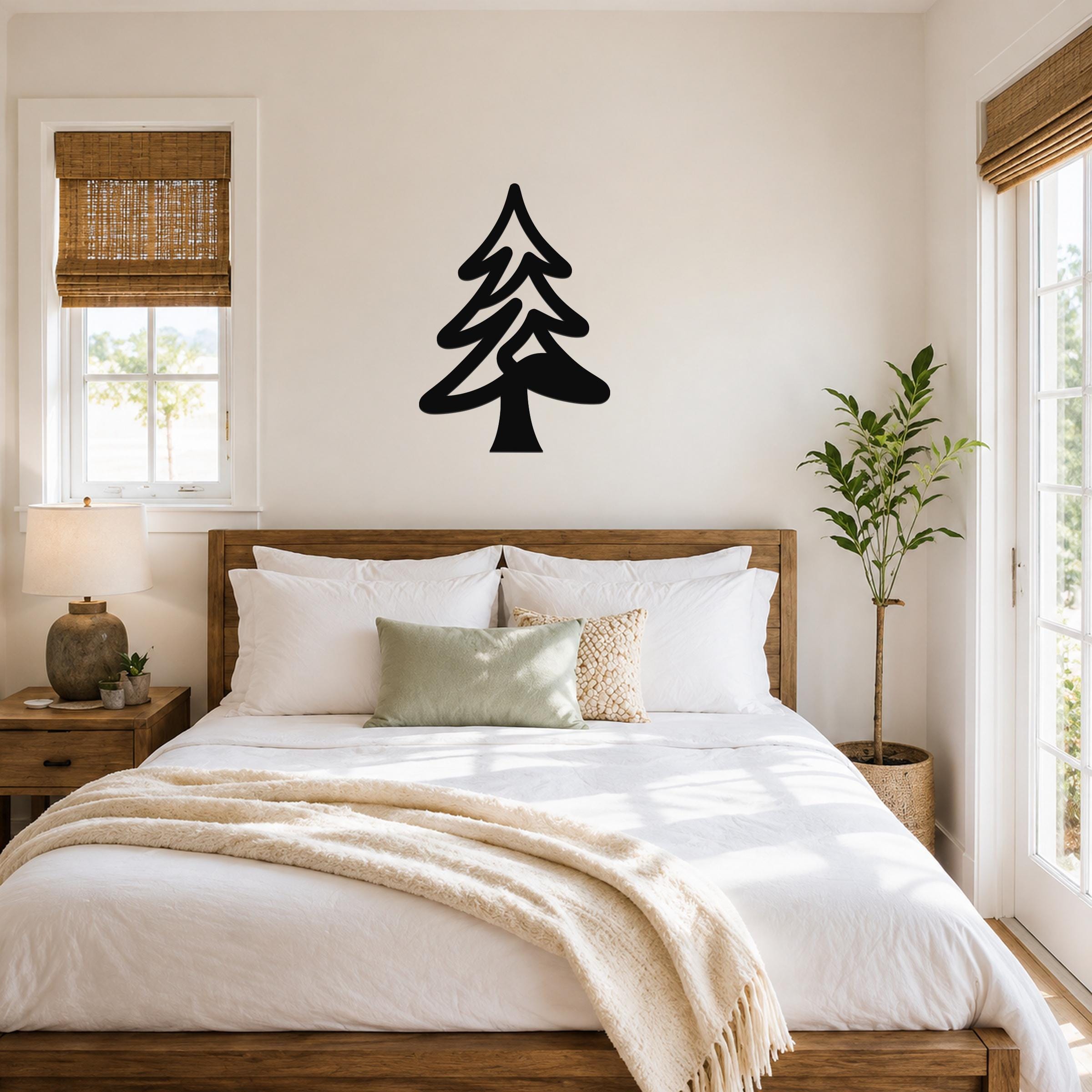 Black metal pine tree wall art with layered branch cutouts, mounted above a wooden bed in a bright bedroom.