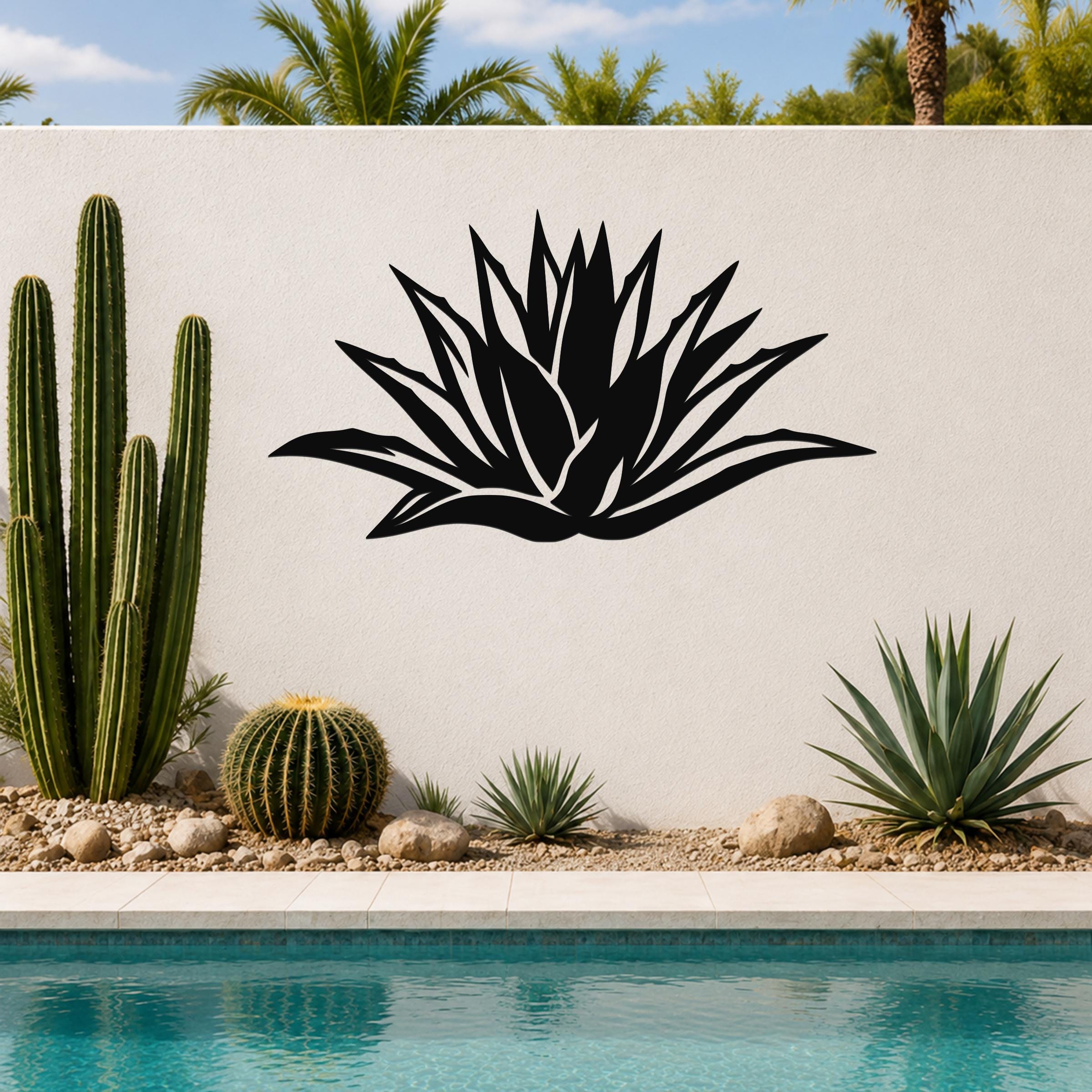 Black metal agave wall art with leaf cutouts, mounted on a white outdoor wall above a poolside garden.